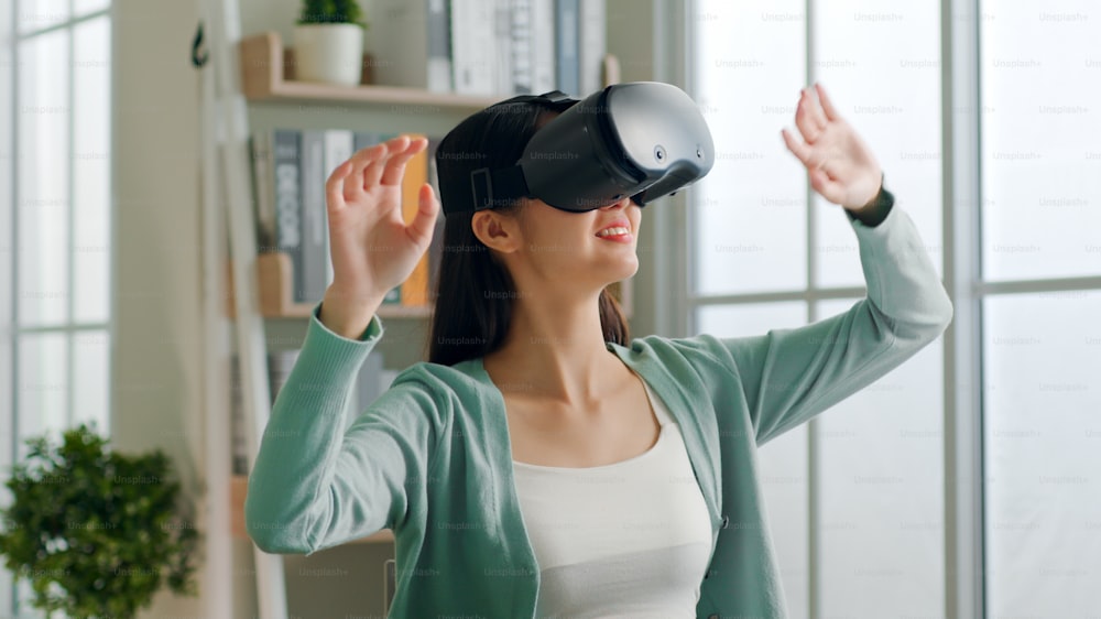 Joven asiática que se siente emocionada mientras usa auriculares 360 VR para realidad virtual, metaverso en casa