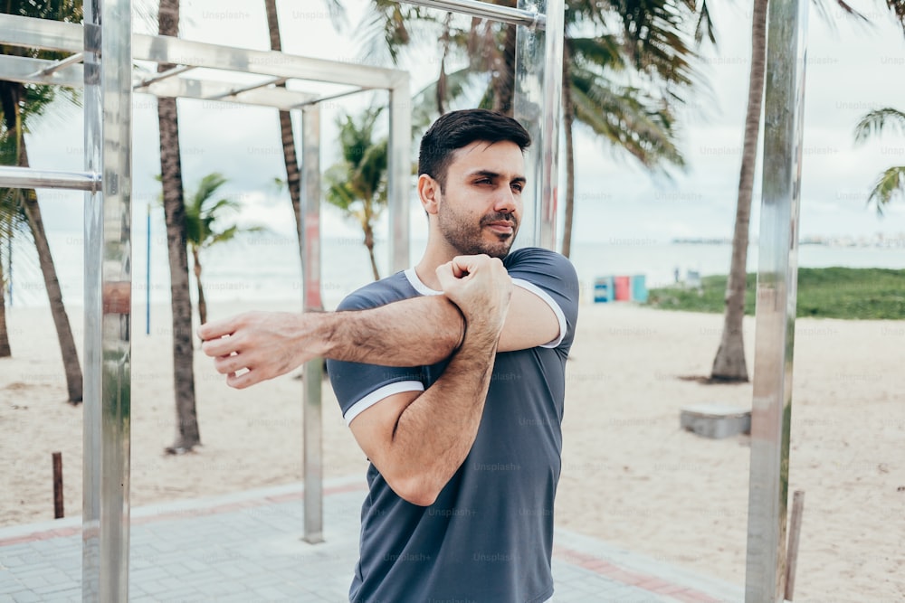 Handsome young man doing street workout on the beach