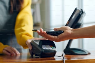 Cliente usando telefone para pagamento no café-restaurante, tecnologia cashless e conceito de transferência de dinheiro