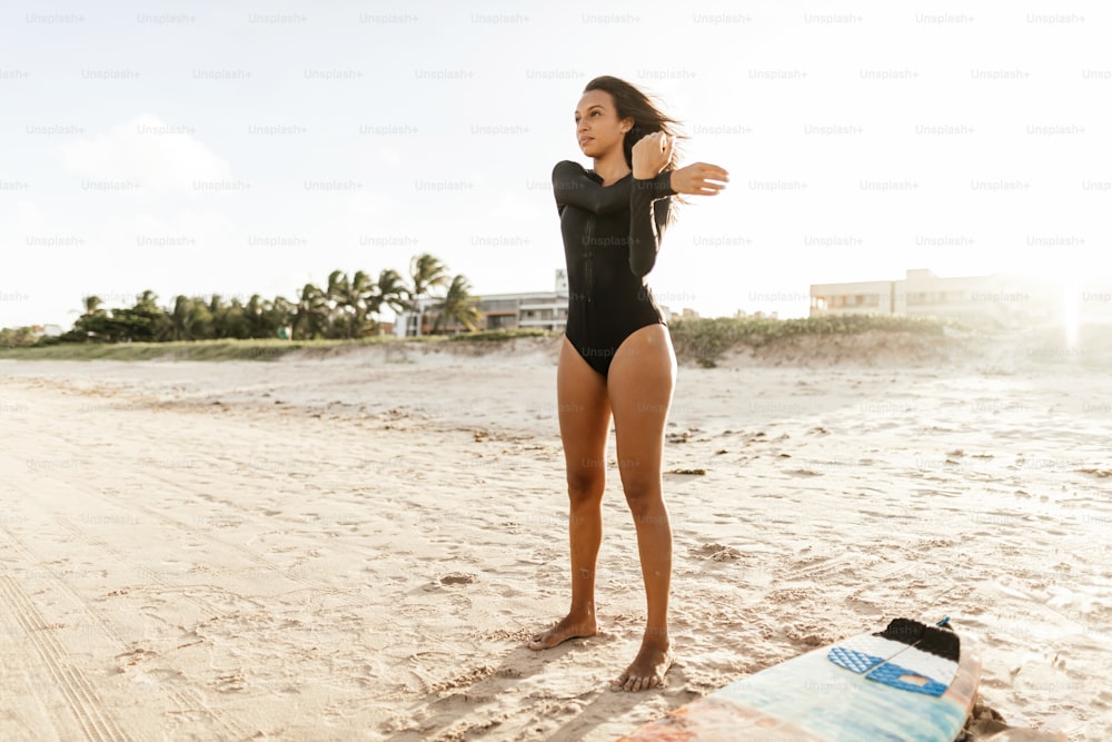 A young surfer girl on the beach stretching before going into the sea
