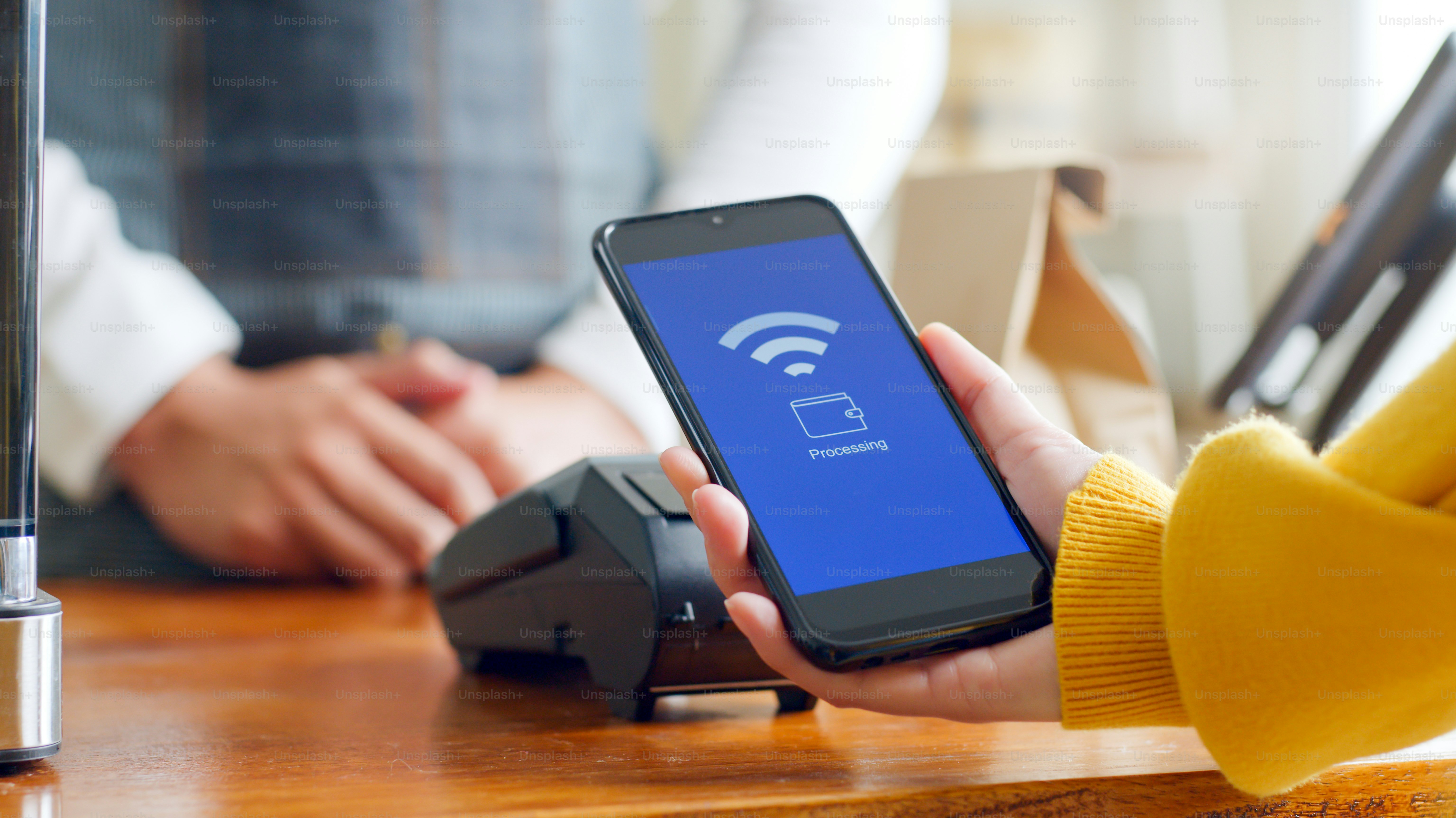 El cliente usa un teléfono inteligente para el pago NFC en el restaurante cafetería, tecnología sin efectivo, sin contacto y concepto de transferencia de dinero
