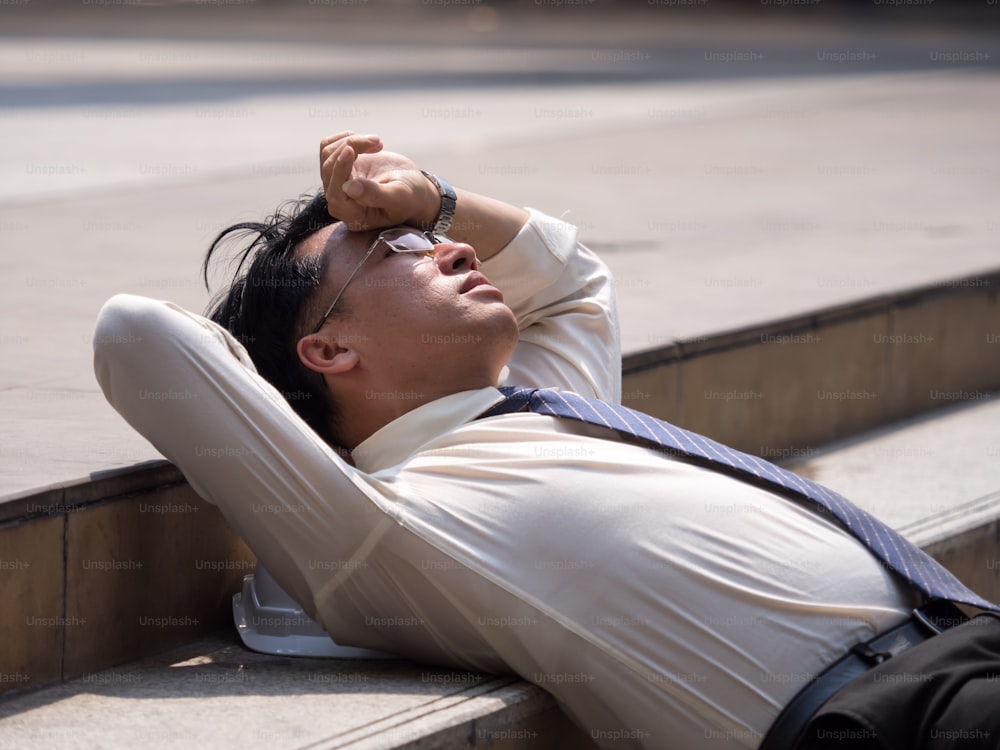 Sconvolto uomo d'affari asiatico anni '40 stanco dal lavoro seduto alle scale, disoccupazione, licenziato dal lavoro, deluso, perdita e sentimento giù concetto