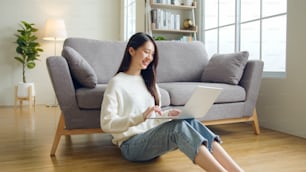 Young Asian woman using laptop computer for online working, studying, learning chatting in social media at home, woman lifestyle at home concept