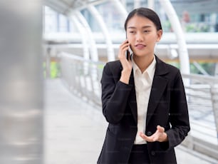 Portrait young Asian businesswoman 20-30s holding smart phone in formal suit at the modern city