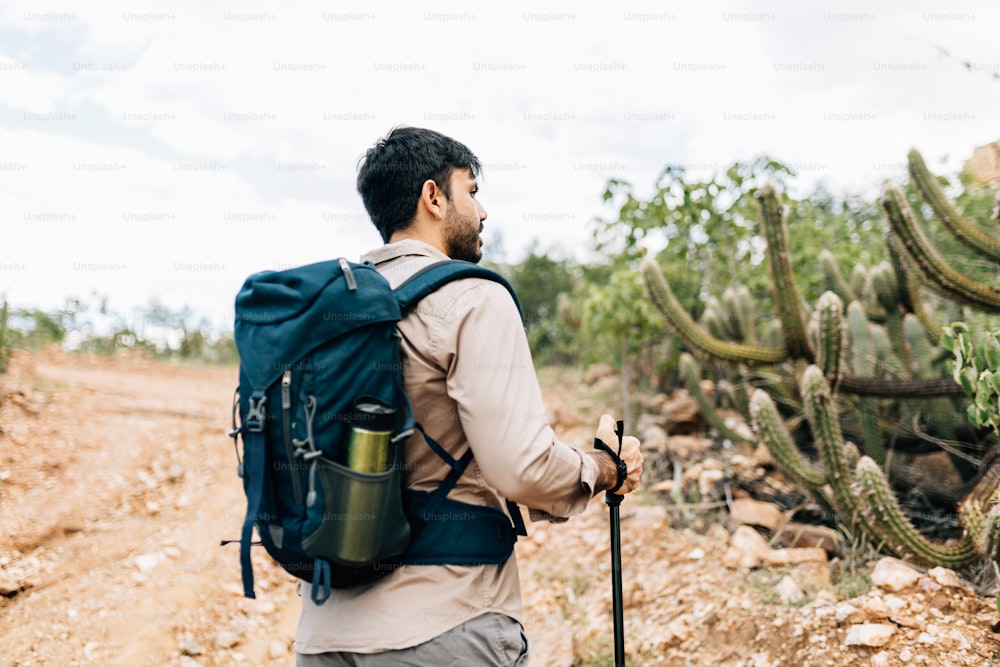 Homem caminhando com mochila e bastões de trekking na Caatinga Brasileira