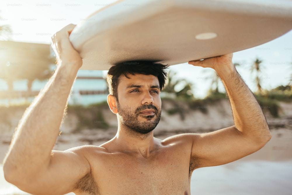 Porträt eines brasilianischen Surfers am Strand, der sein Bodyboard hochhält. Sport- und Wassersportkonzept.