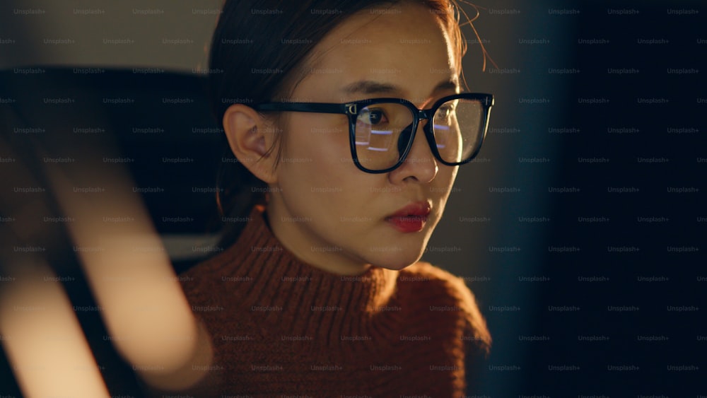 Giovane donna asiatica, programmatrice sviluppatrice, ingegnere del software, supporto IT, che indossa occhiali che lavorano duramente di notte sul computer per controllare la codifica nel sistema di bug e l'esecuzione del programma con successo.