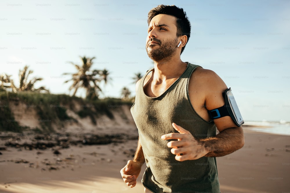 Athletic man running at the beach. Sport, fitness and healthy lifestyle.