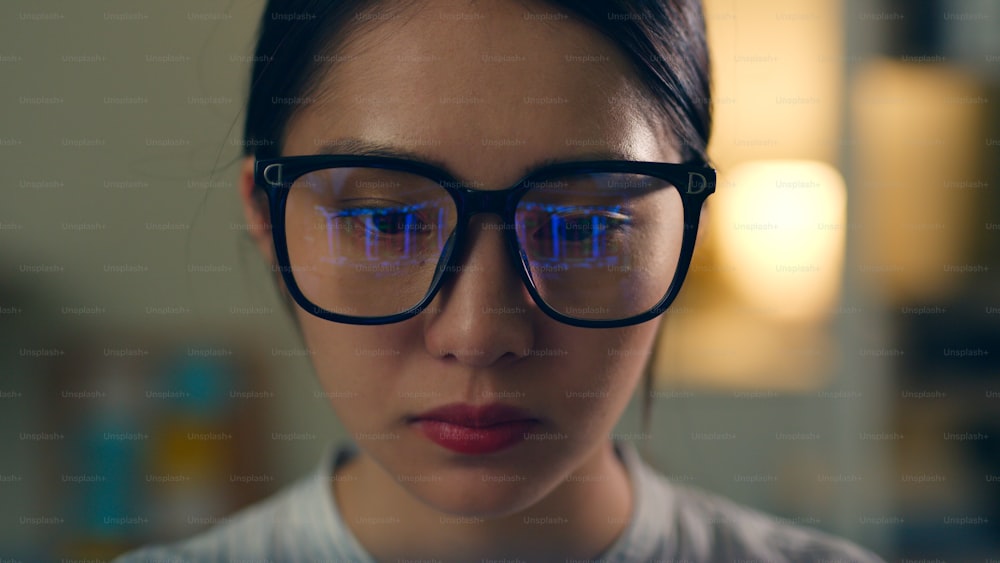 Aktienhändlerin mit Brille, die auf den Computerbildschirm schaut, der sich in einer Brille widerspiegelt, die den Aktienhandelsgraphen analysiert. Nahaufnahme der Augen Refektion