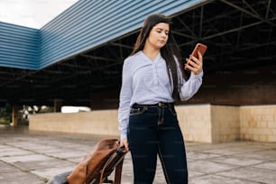 Femme voyageuse marchant à la gare avec une valise et un téléphone portable