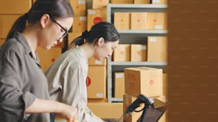 Femme asiatique travaillant à l’entrepôt de magasin en ligne emballant le produit aux boîtes en carton de colis, concept de petite entreprise de vente au détail de commerce électronique en ligne