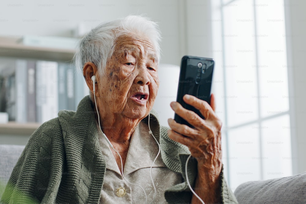 Mujer mayor asiática cabello gris 80-90s videollamada con médico, concepto de telemedicina telesalud