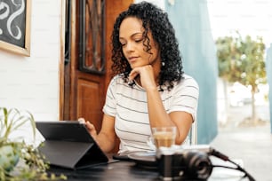 Mujer usando tableta digital mientras está sentada en un café en la acera