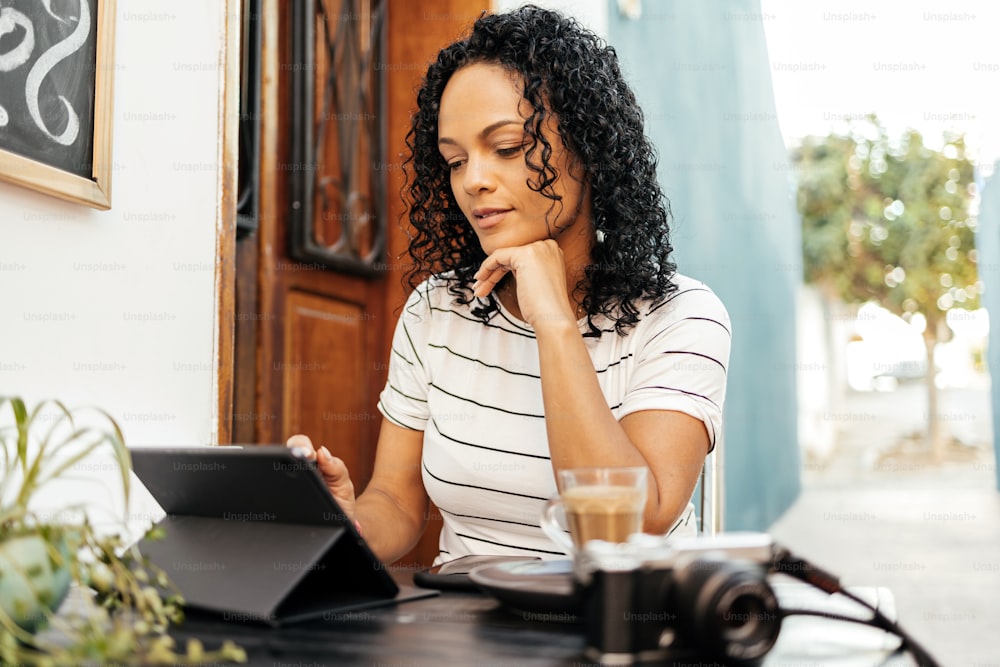 Woman using digital tablet while sitting at sidewalk cafe