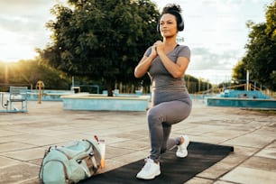 Fitness girl doing lunge in urban park