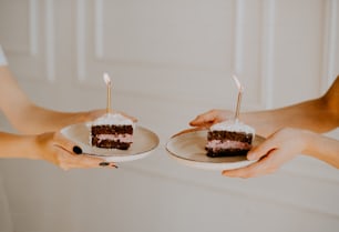 two people holding plates with two slices of cake