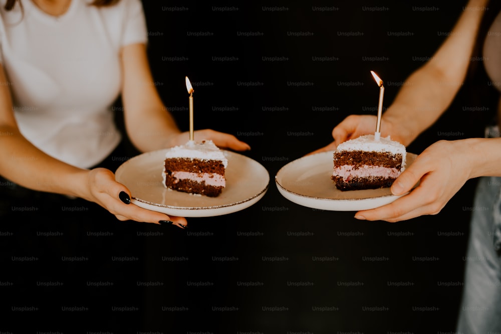 two people holding plates with a piece of cake on them