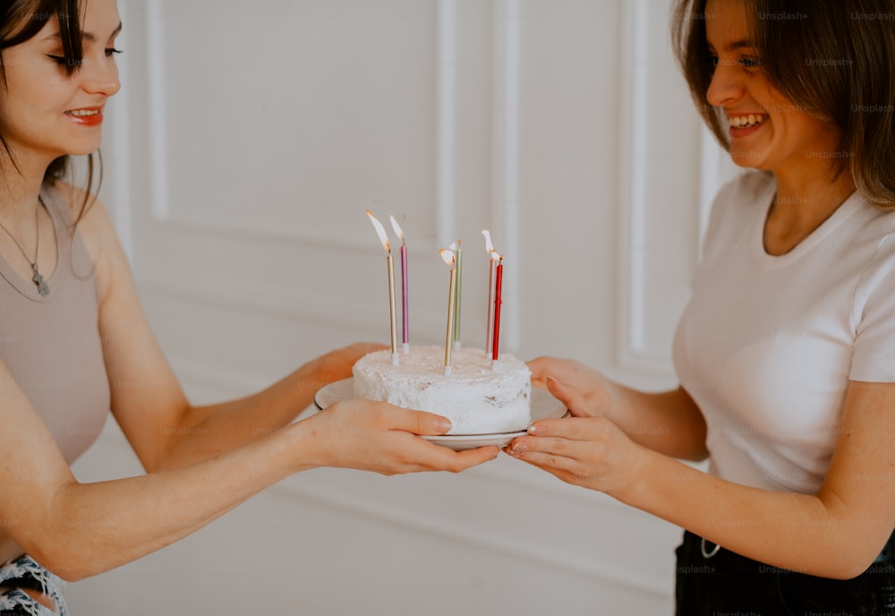 two women holding a cake with candles on it