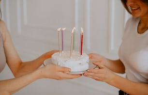 two women holding a cake with candles on it