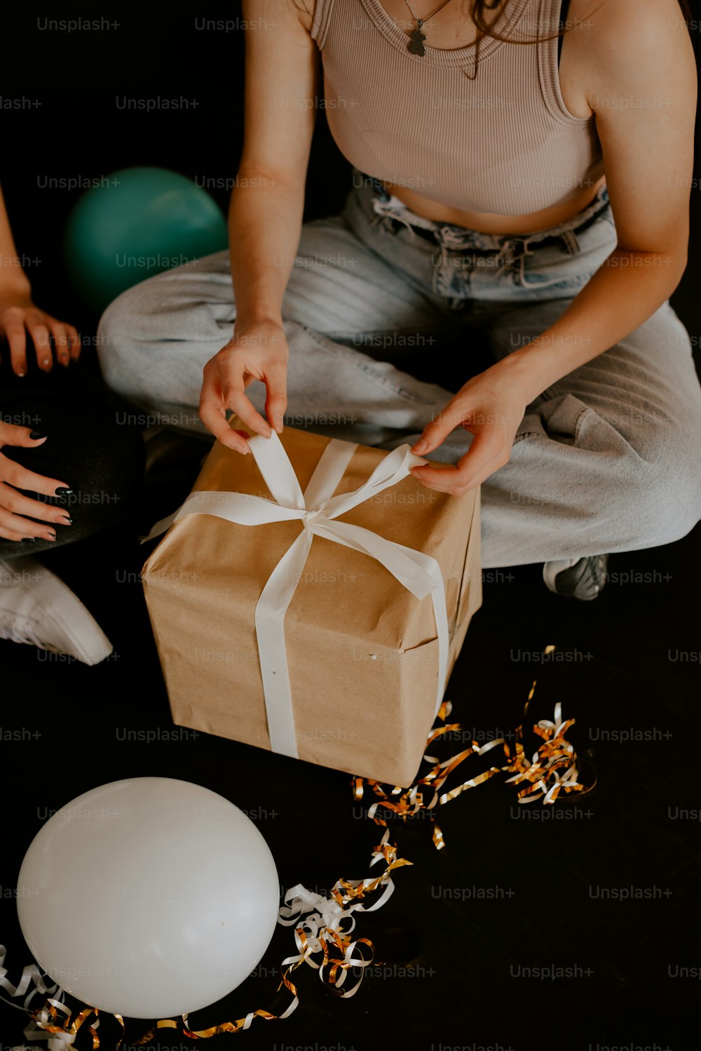 a woman opening a brown box with a white ribbon