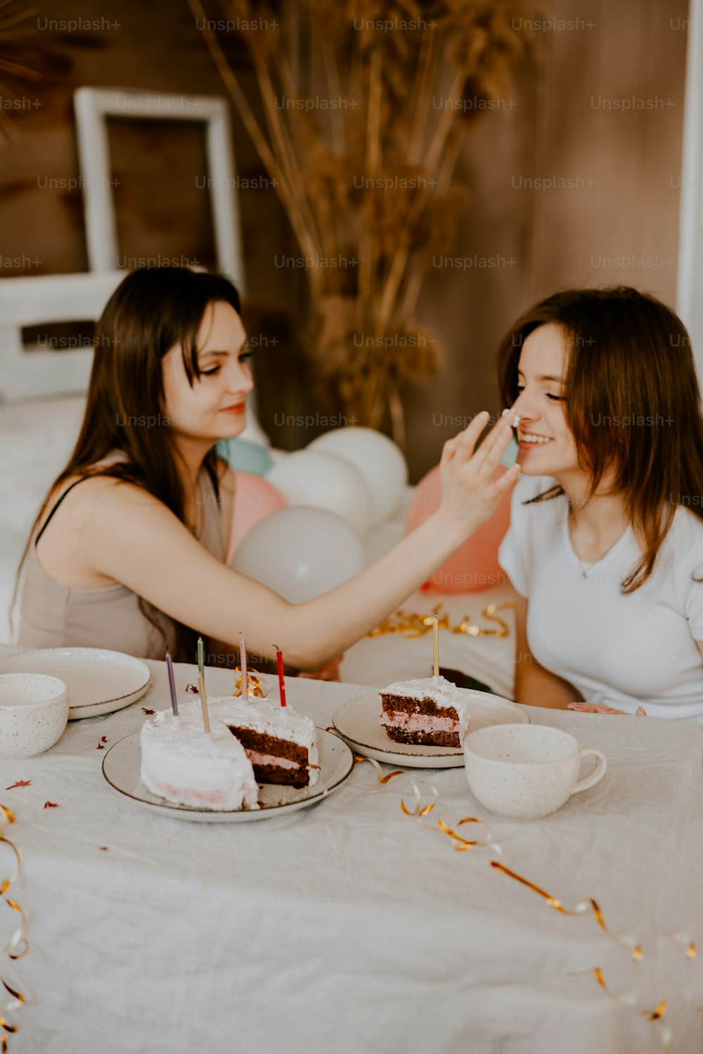 two women sitting at a table eating cake