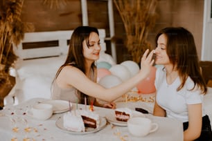 two women sitting at a table eating cake