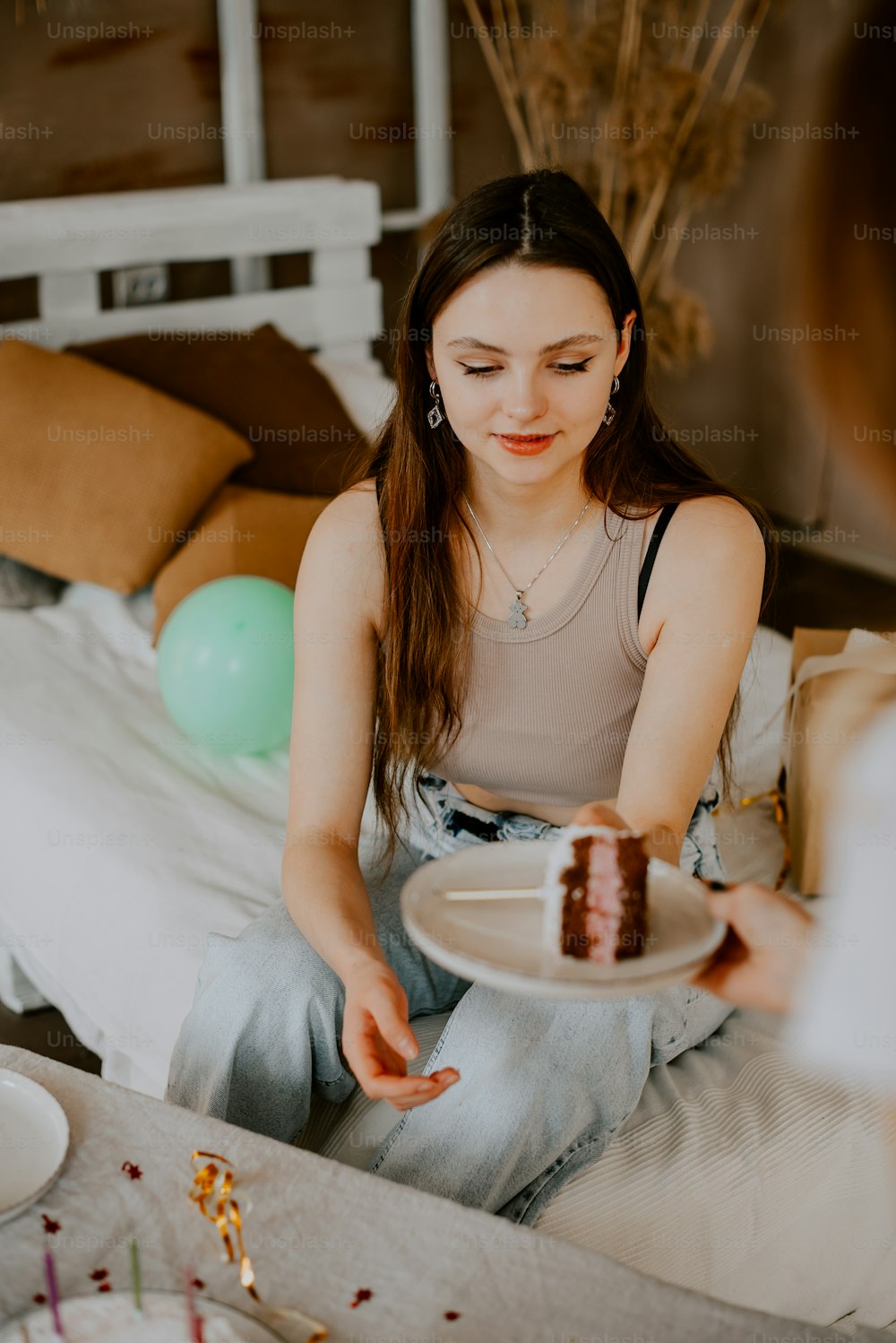 Eine Frau, die auf einem Bett sitzt und einen Teller mit einem Stück Kuchen darauf hält