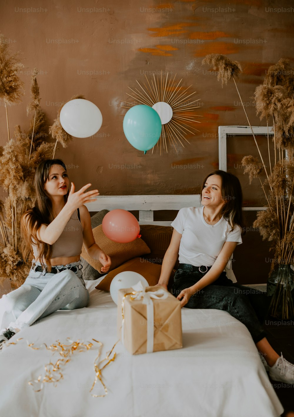 two women sitting on a bed with balloons