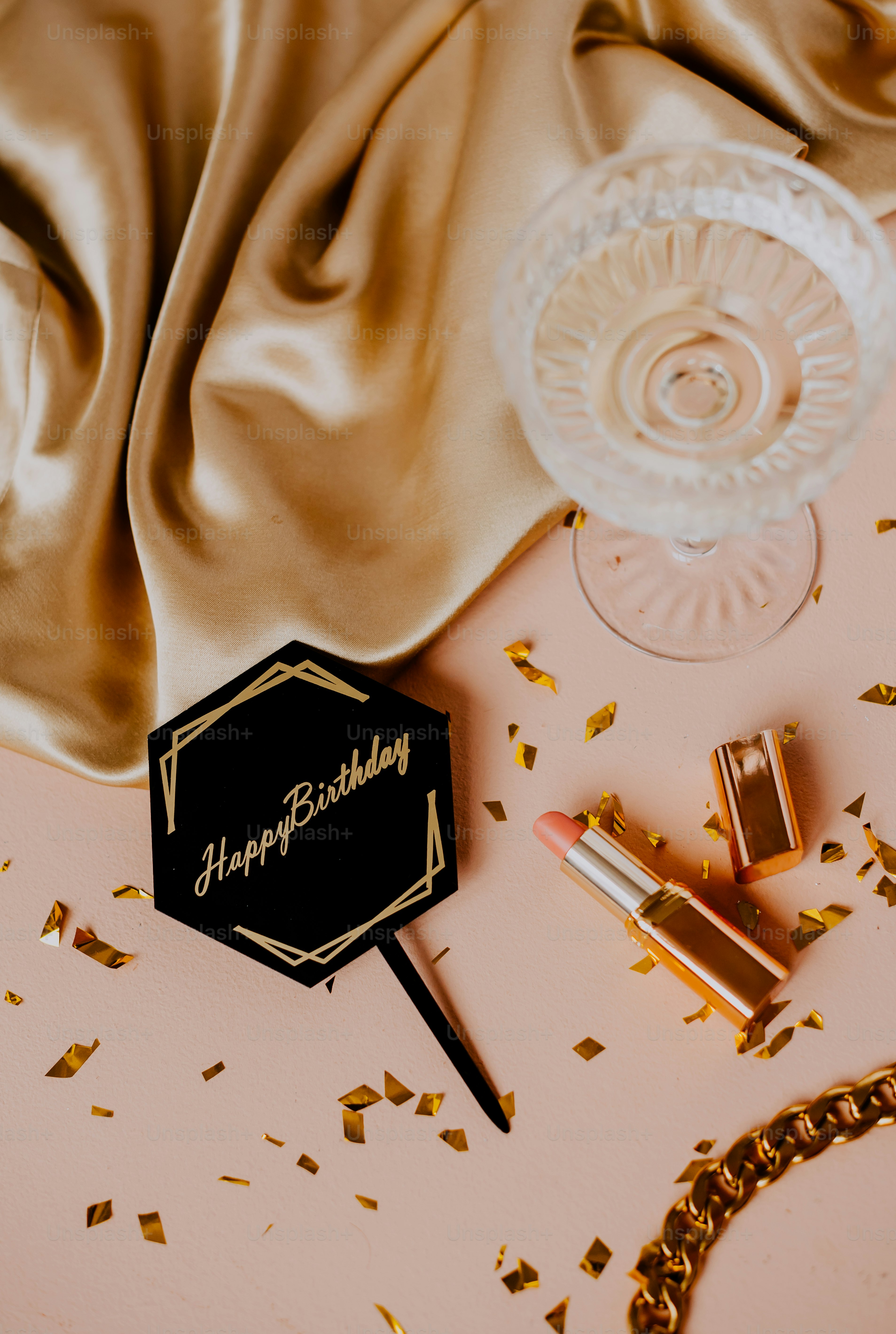 a pink table topped with gold confetti and lipstick