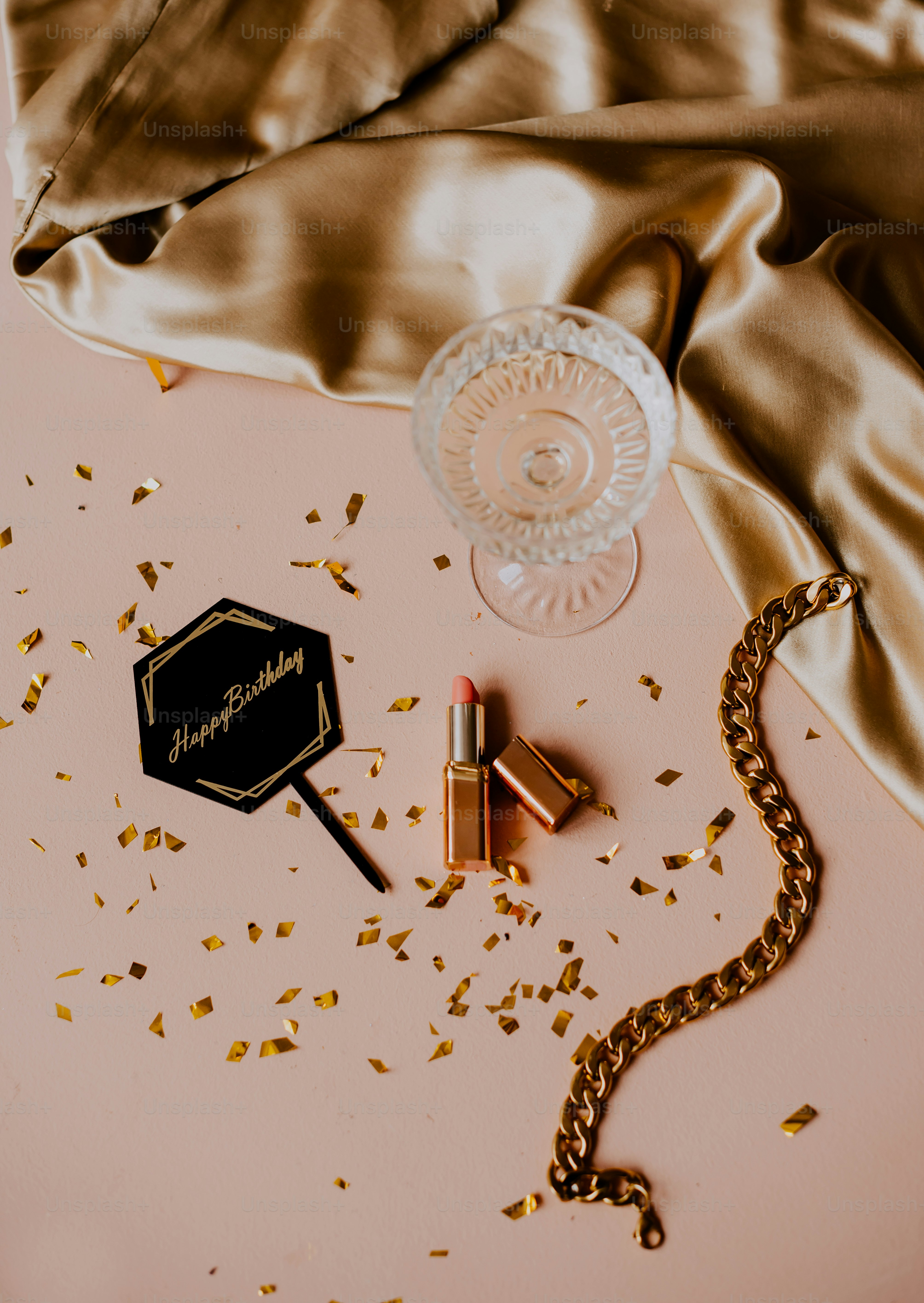 a table topped with a bottle of lipstick and a necklace