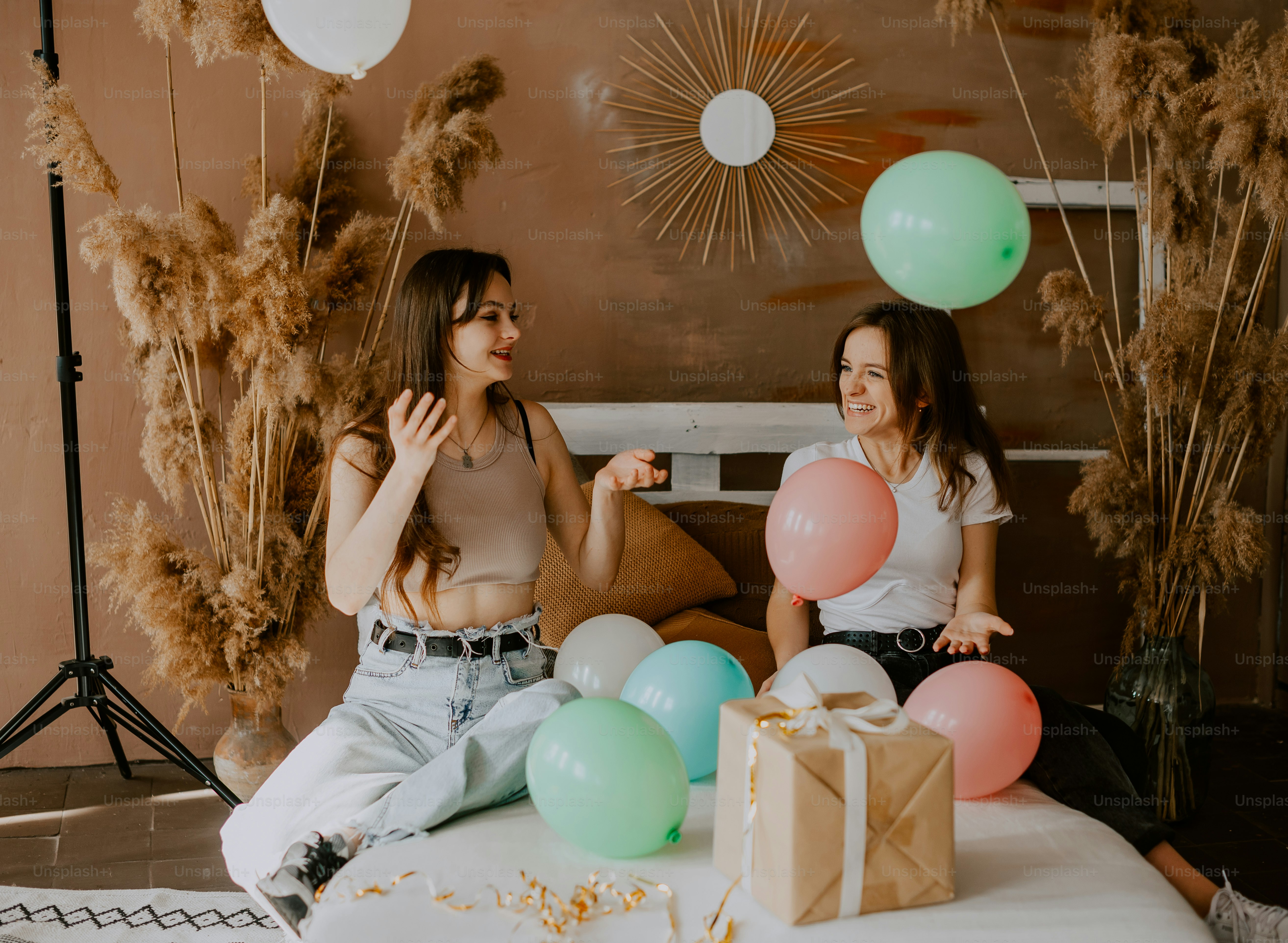 two women sitting on a bed with balloons