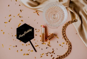 a pink table with a gold chain, lipstick, and a bottle of lipstick