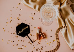 a bottle of lipstick next to a golden chain