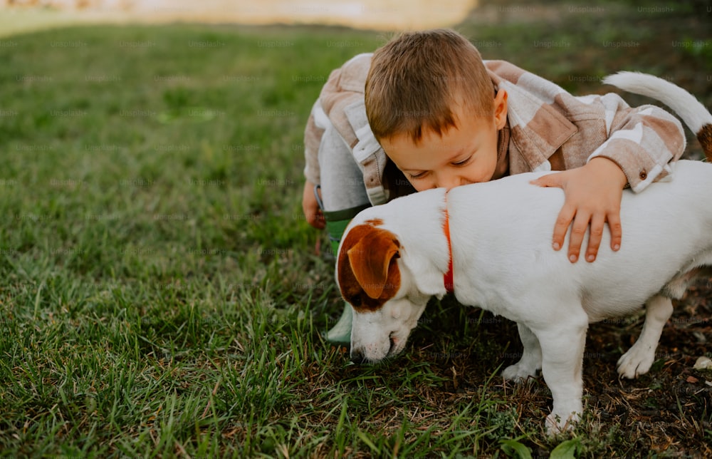 um menino brincando com um cachorro na grama