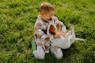 a little boy sitting in the grass with a dog