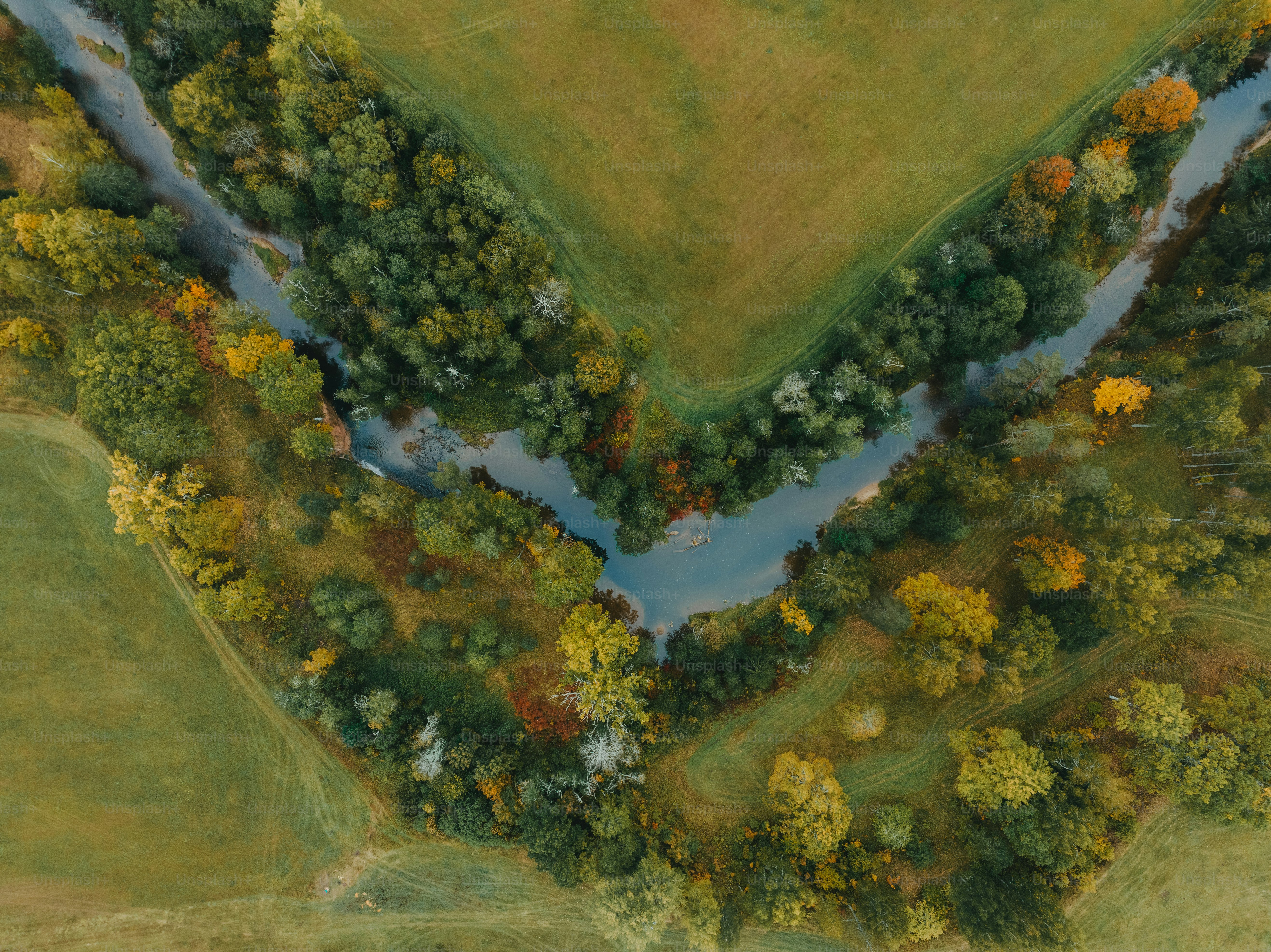 an aerial view of a river running through a lush green field