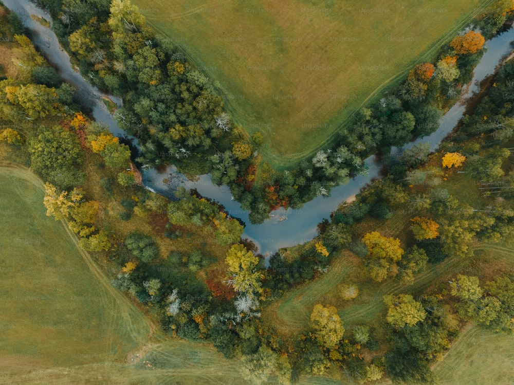 an aerial view of a river running through a lush green field