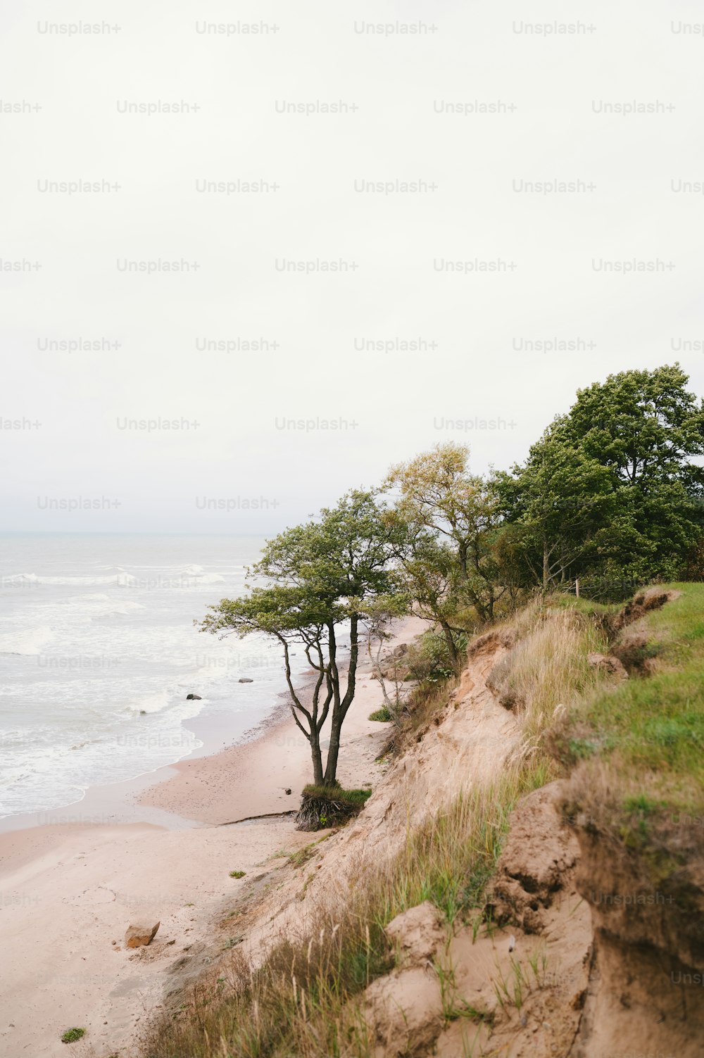 a sandy beach next to the ocean under a cloudy sky