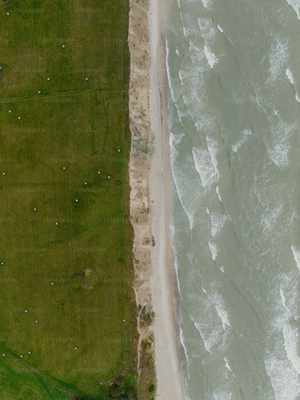 an aerial view of a beach and grassy area