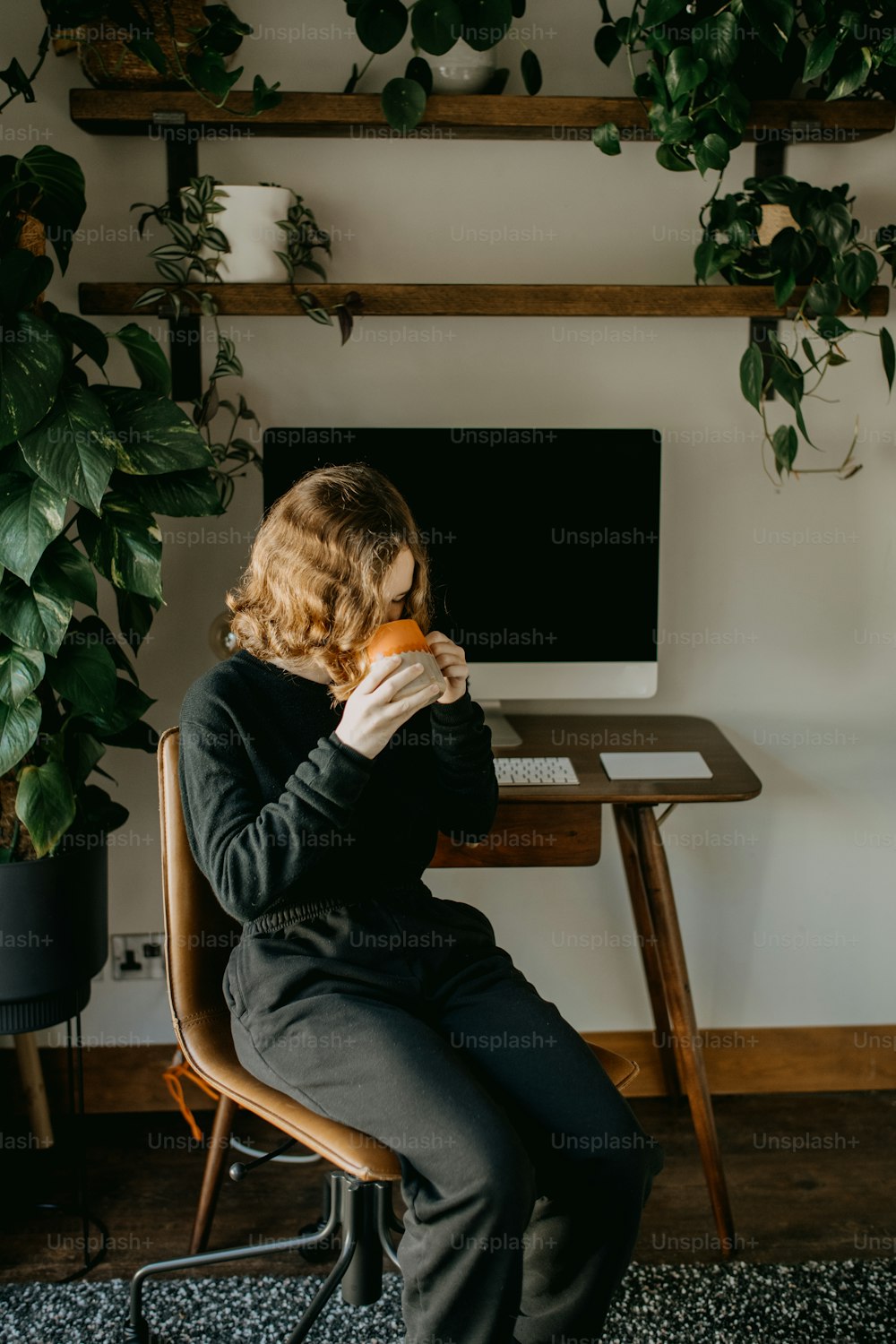 a woman sitting at a desk eating a donut