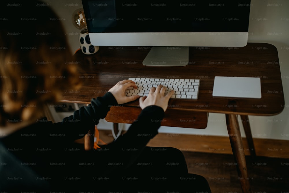 Una mujer está escribiendo en el teclado de una computadora