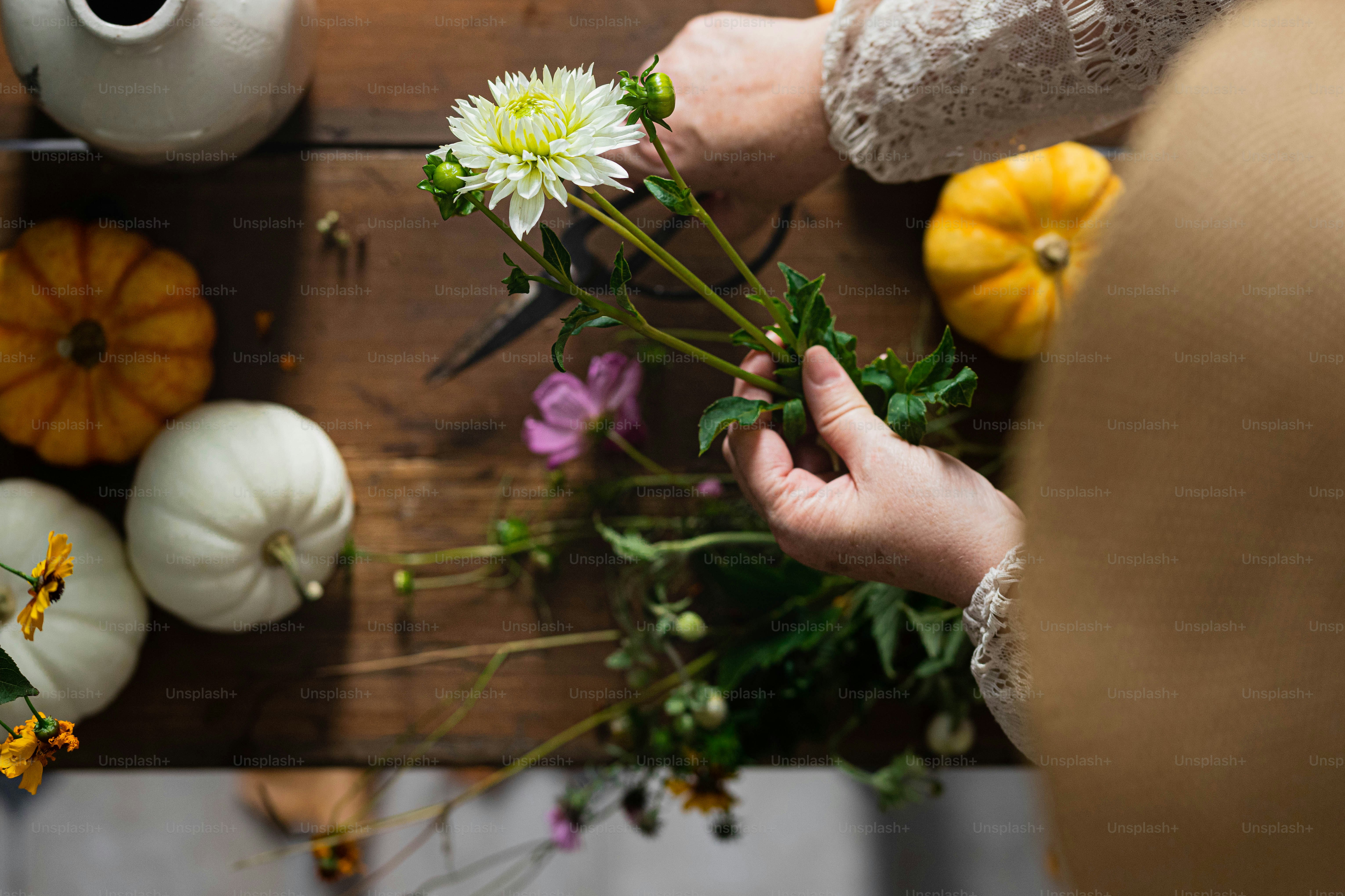 a person arranging flowers on a wooden table