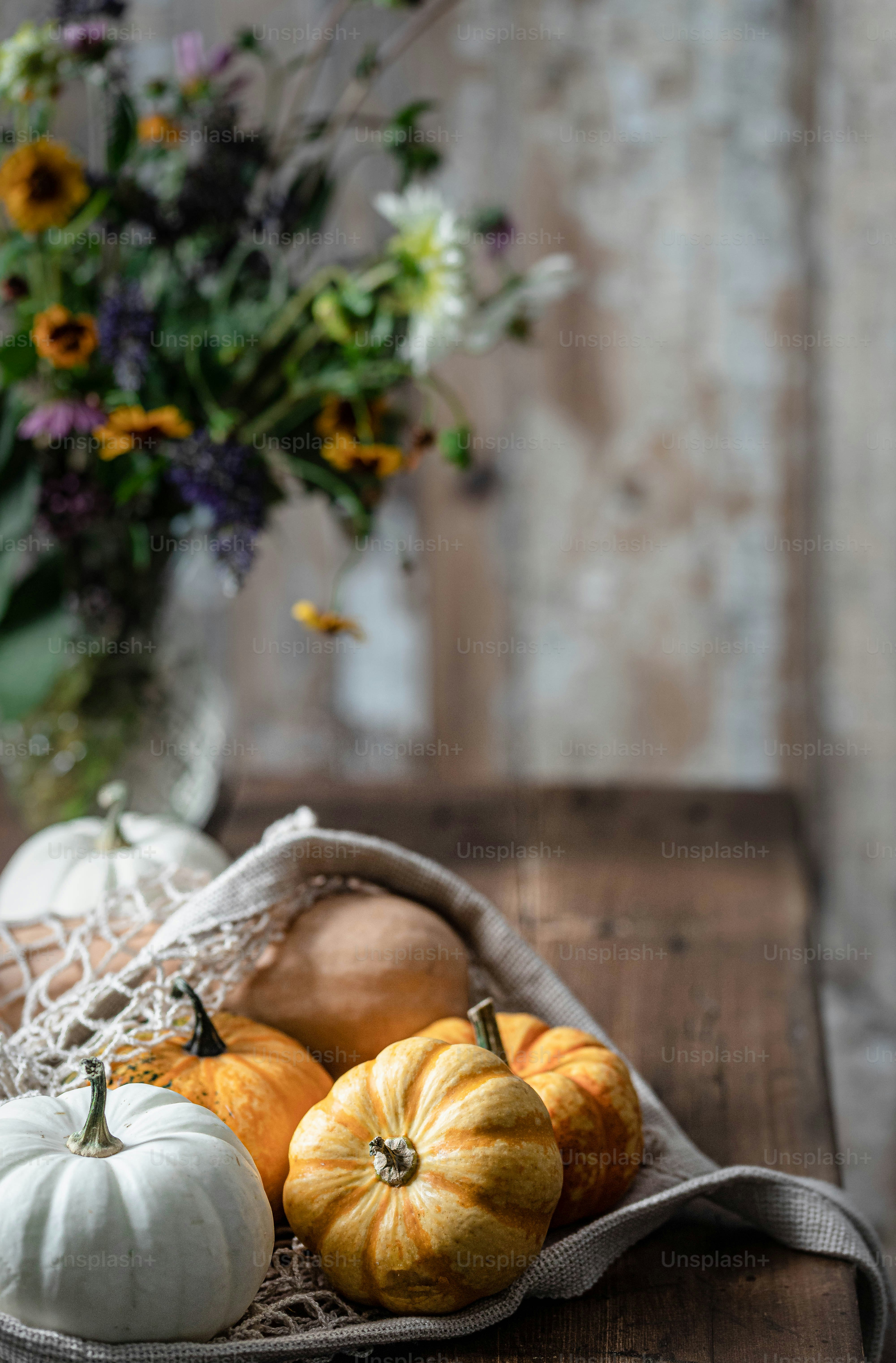 un cesto pieno di zucche seduto sopra un tavolo di legno