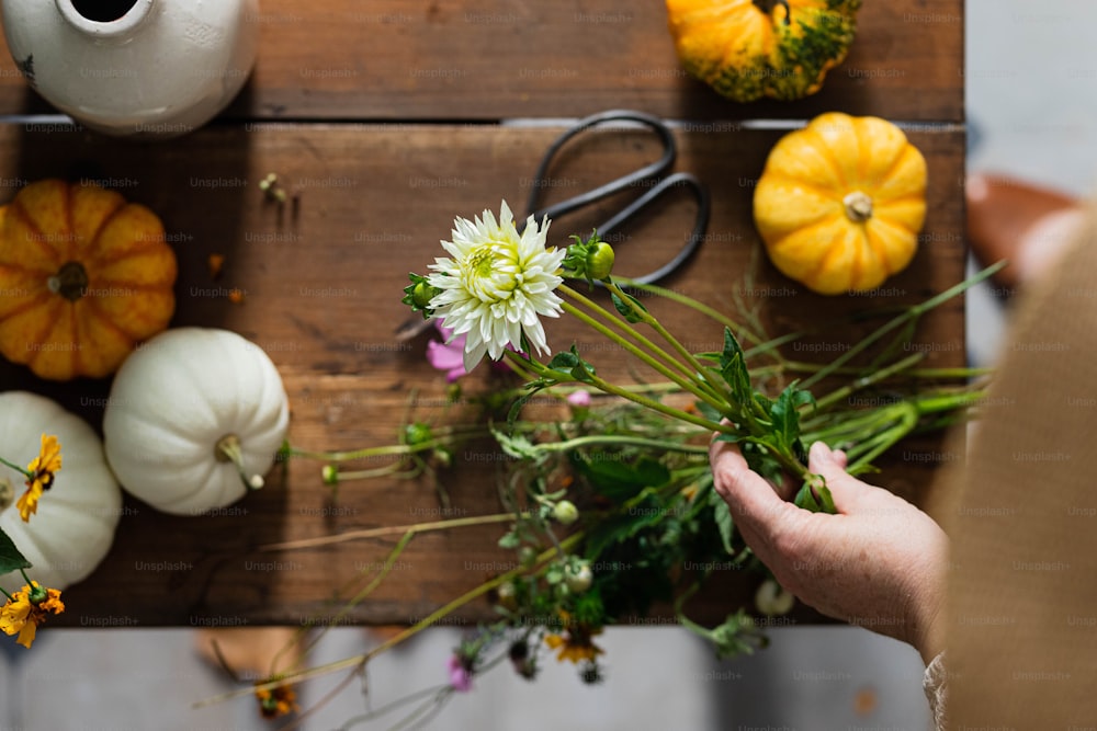 eine person, die einen blumenstrauß auf einem holztisch hält