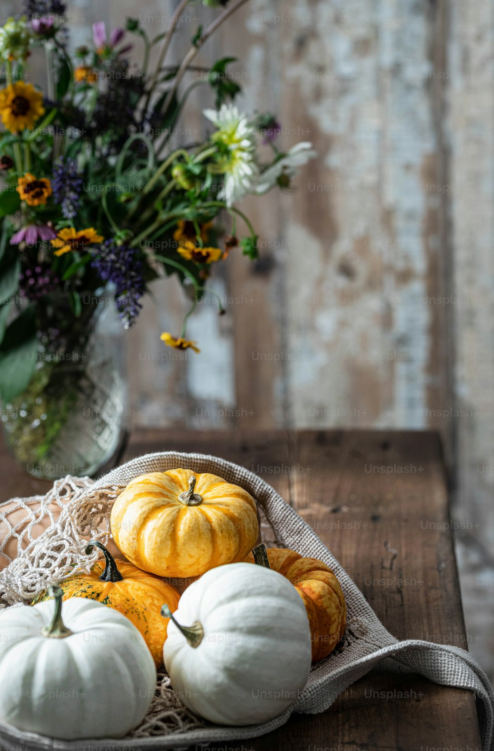 a basket filled with white pumpkins on top of a wooden table