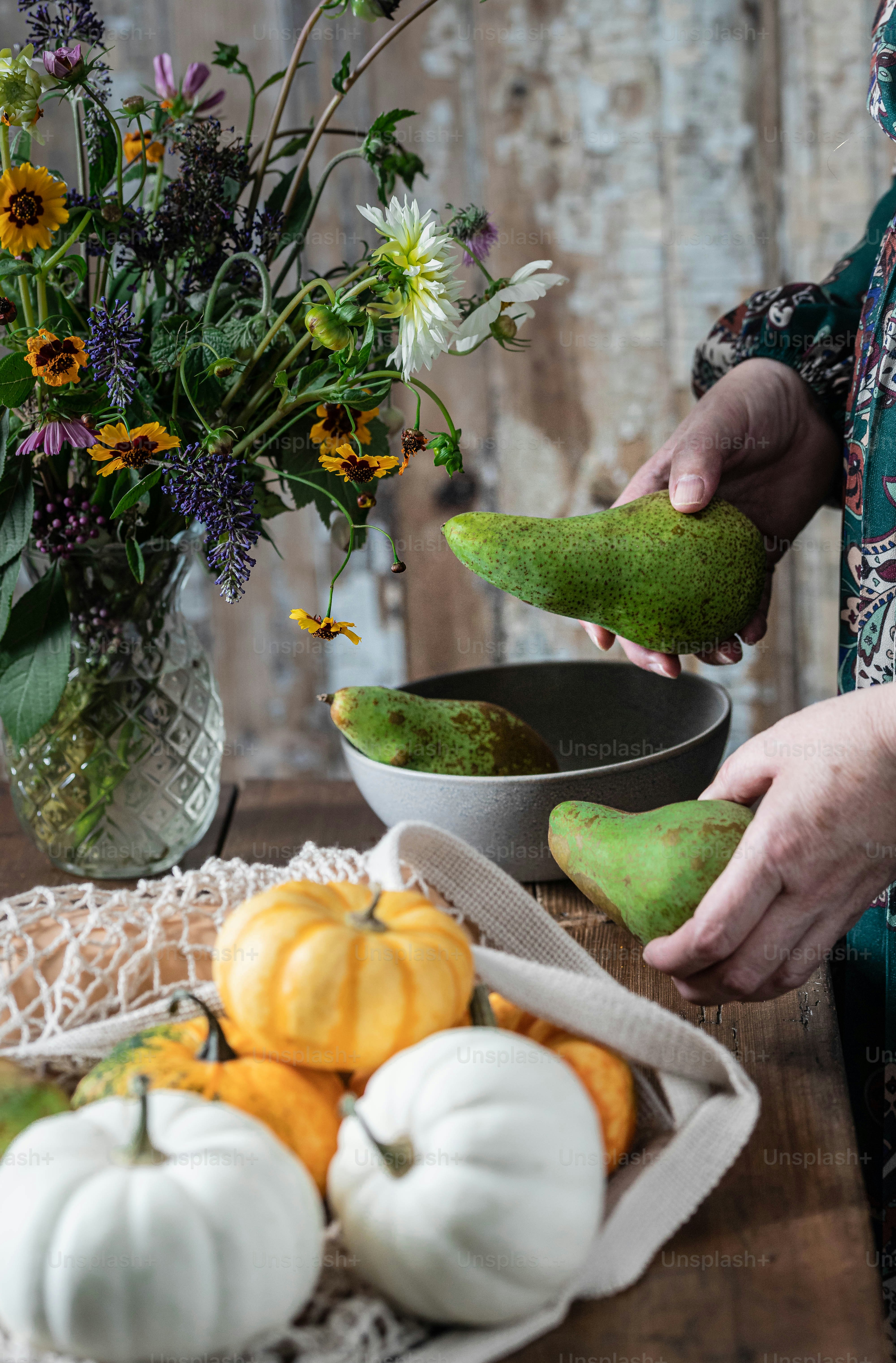 a woman is peeling an avocado on a table