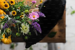 a black cat sniffing a bouquet of flowers