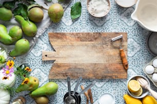 a wooden cutting board surrounded by various kitchen utensils