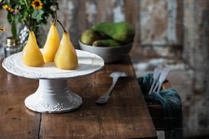 three pears on a white plate on a wooden table