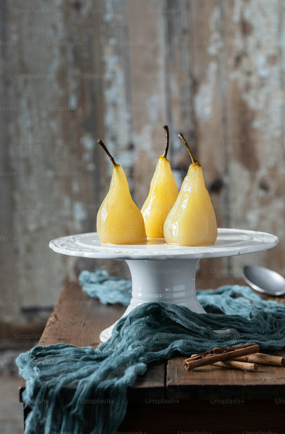 three pears on a cake plate with a spoon